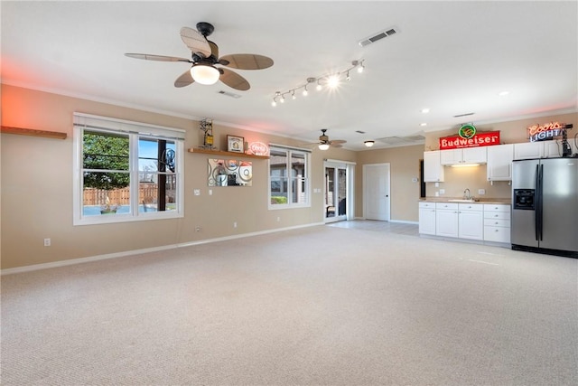 unfurnished living room featuring crown molding, light carpet, a sink, and visible vents