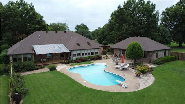 pool with a deck, an outbuilding, a diving board, a lawn, and a patio area