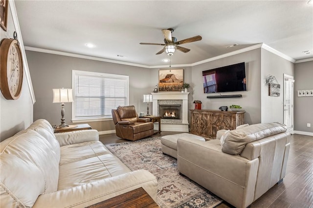 living area with visible vents, baseboards, wood finished floors, crown molding, and a fireplace