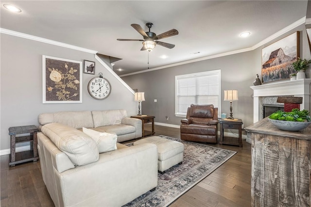 living area with a fireplace, dark wood-type flooring, a ceiling fan, ornamental molding, and baseboards