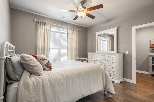 bedroom with ceiling fan, dark wood-type flooring, visible vents, and baseboards