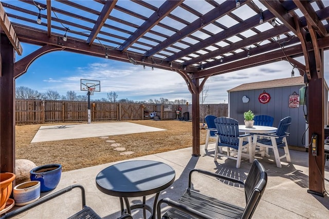 view of patio / terrace with an outbuilding, outdoor dining space, a fenced backyard, and a pergola