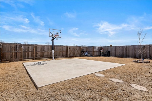 view of basketball court with a fenced backyard, basketball court, and a lawn