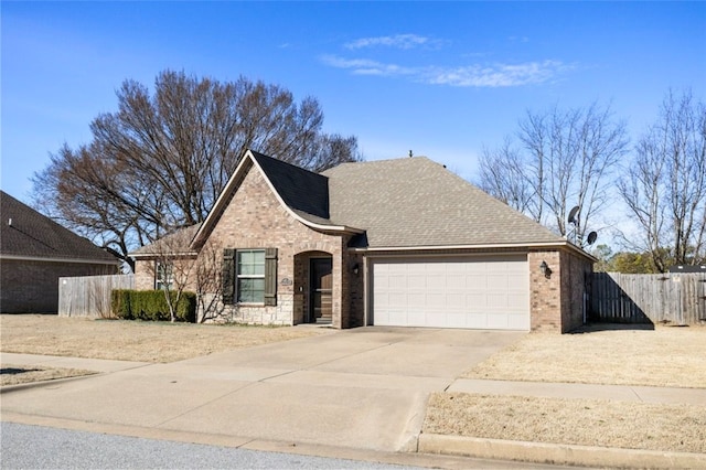 view of front facade with an attached garage, brick siding, a shingled roof, fence, and driveway