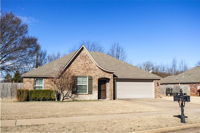 view of front of property featuring a garage, brick siding, driveway, and fence