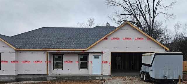 property under construction featuring an attached garage and roof with shingles