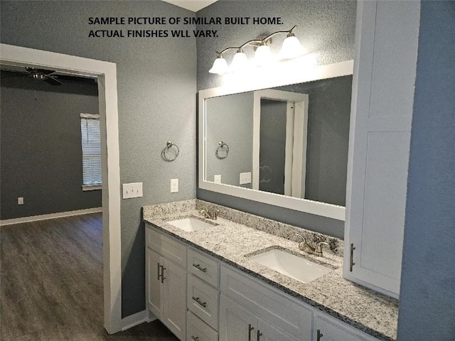 bathroom featuring double vanity, a sink, baseboards, and wood finished floors