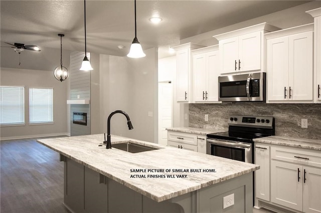 kitchen with appliances with stainless steel finishes, a sink, a kitchen island with sink, and decorative backsplash