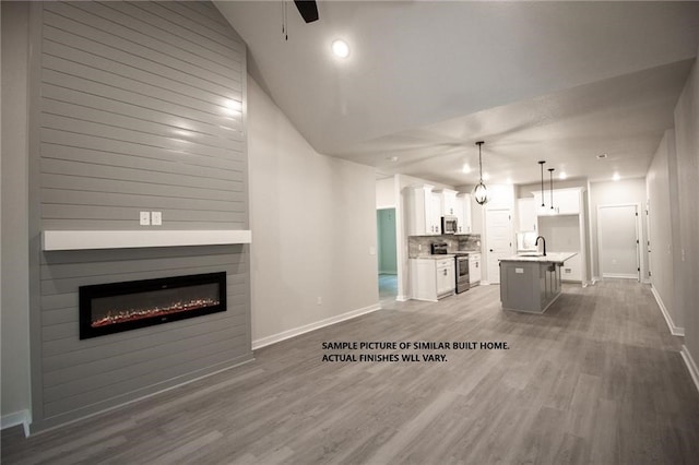 living room with a glass covered fireplace, wood finished floors, and baseboards