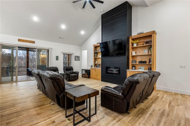 living room with a large fireplace, light wood finished floors, baseboards, high vaulted ceiling, and recessed lighting