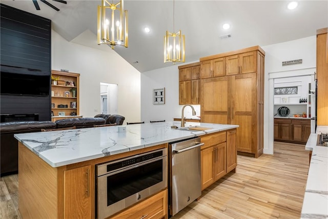 kitchen featuring a center island with sink, appliances with stainless steel finishes, open floor plan, light wood-type flooring, and a sink