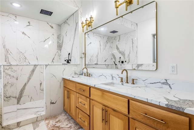 full bathroom with marble finish floor, a sink, a marble finish shower, and double vanity