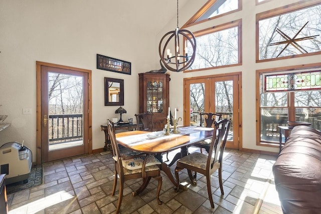 dining area with high vaulted ceiling, french doors, a notable chandelier, and stone tile floors