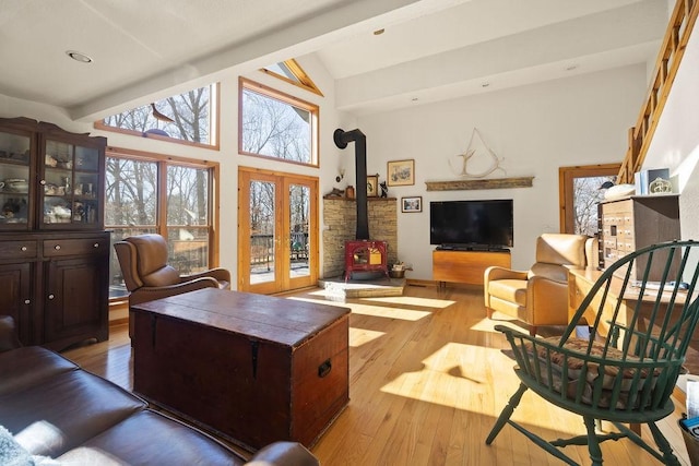 living area featuring french doors, beam ceiling, a wood stove, high vaulted ceiling, and hardwood / wood-style flooring