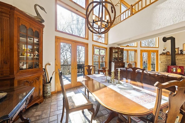 dining room with a wood stove, an inviting chandelier, stone tile floors, and french doors