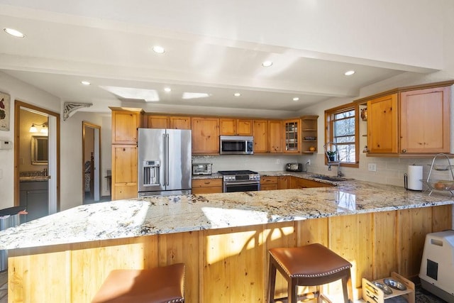 kitchen with decorative backsplash, appliances with stainless steel finishes, a sink, beamed ceiling, and a peninsula