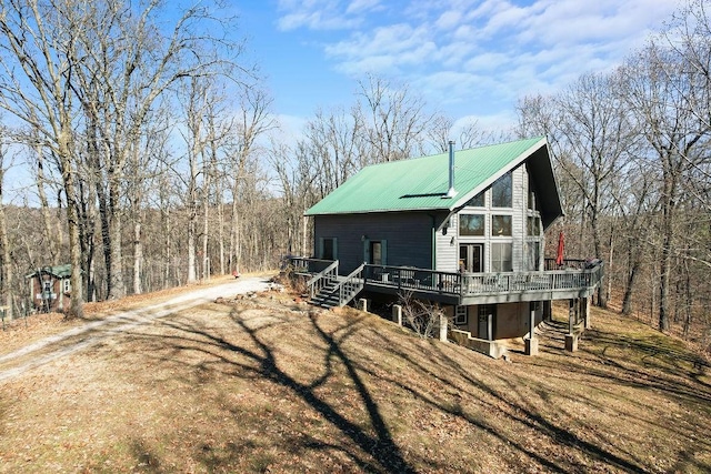 view of front of house featuring stairs, dirt driveway, metal roof, and a wooden deck