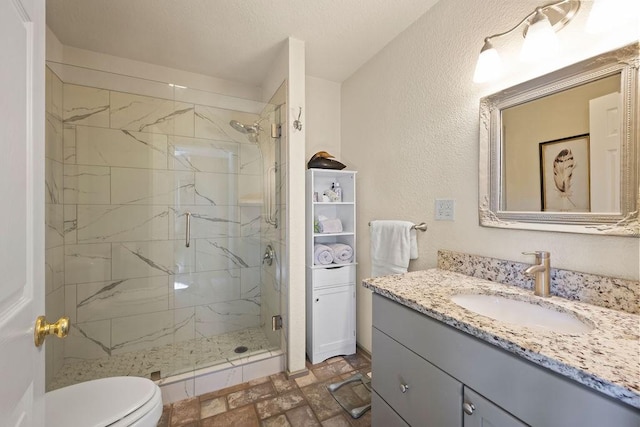 bathroom featuring a marble finish shower, a textured wall, toilet, vanity, and a textured ceiling