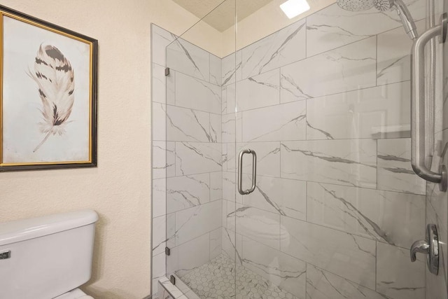 full bath featuring a textured wall, a shower stall, and toilet