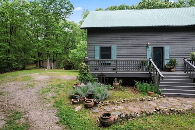 view of side of home with driveway, metal roof, and a deck