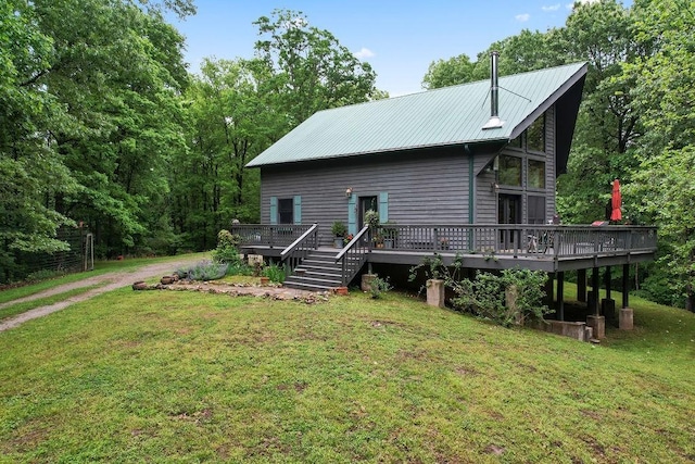 view of front of property with driveway, metal roof, a deck, and a front lawn