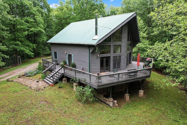 rear view of property featuring metal roof, a lawn, and a deck