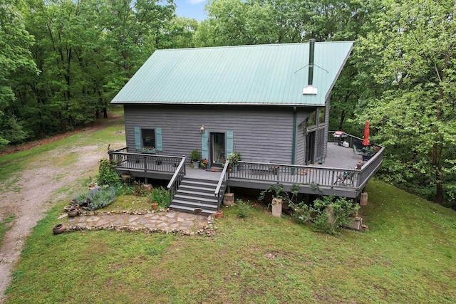 view of front facade featuring a deck, driveway, a front lawn, and metal roof