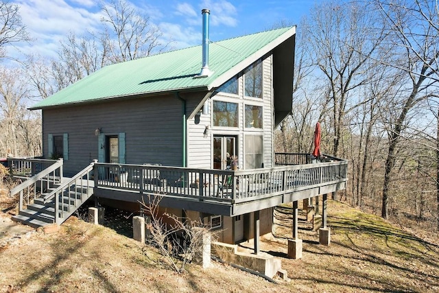 rear view of house with metal roof, a wooden deck, and stairs