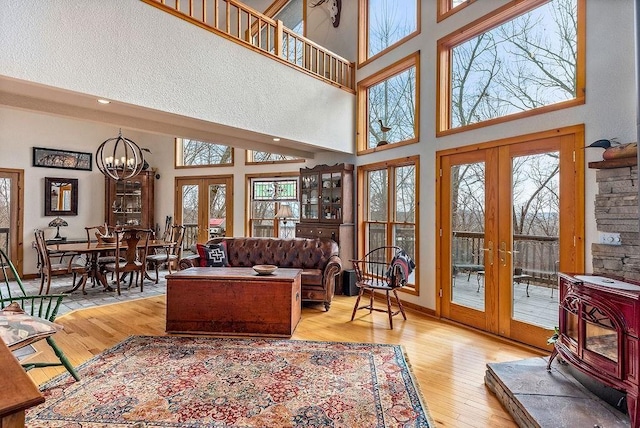 living room with french doors, a towering ceiling, hardwood / wood-style floors, an inviting chandelier, and baseboards