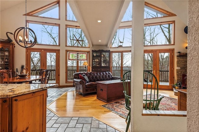 living room with high vaulted ceiling, french doors, and stone tile floors