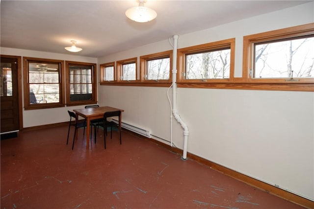 unfurnished dining area with baseboard heating, a healthy amount of sunlight, baseboards, and concrete flooring