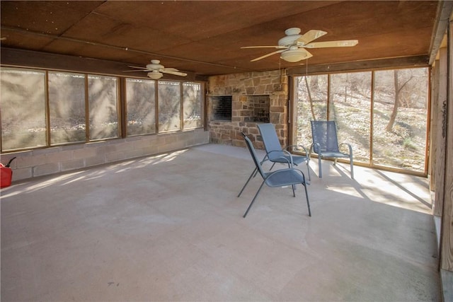 unfurnished sunroom with a fireplace and a ceiling fan