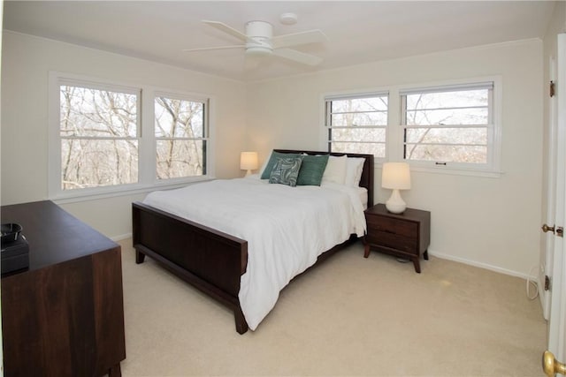 bedroom featuring light carpet, multiple windows, a ceiling fan, and baseboards