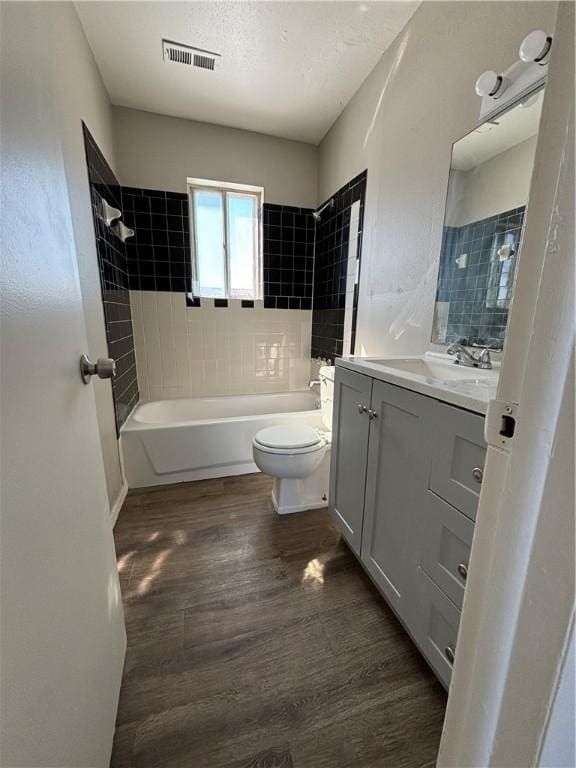 bathroom with visible vents, toilet, wood finished floors, bathtub / shower combination, and vanity