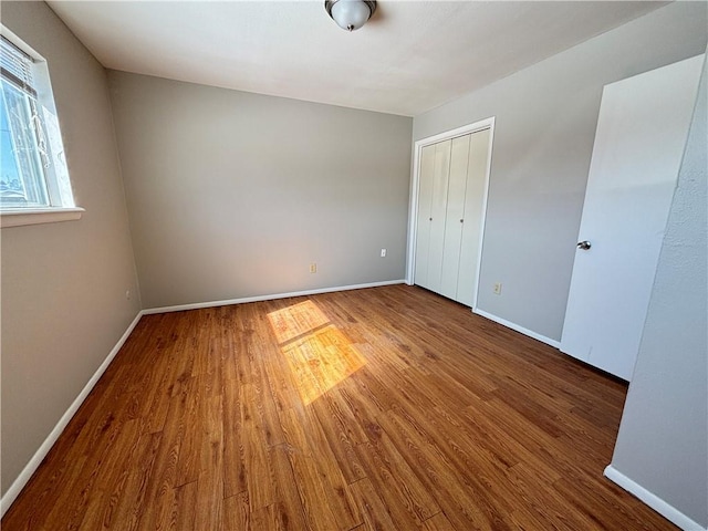 unfurnished bedroom with a closet, baseboards, and wood finished floors