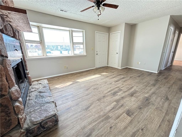 living room with ceiling fan, a brick fireplace, wood finished floors, and visible vents