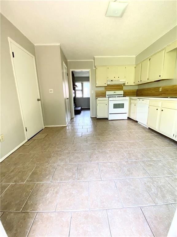 kitchen with white appliances, light tile patterned floors, baseboards, and cream cabinetry