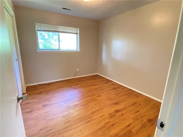 unfurnished bedroom featuring light wood-style floors, baseboards, visible vents, and a textured ceiling