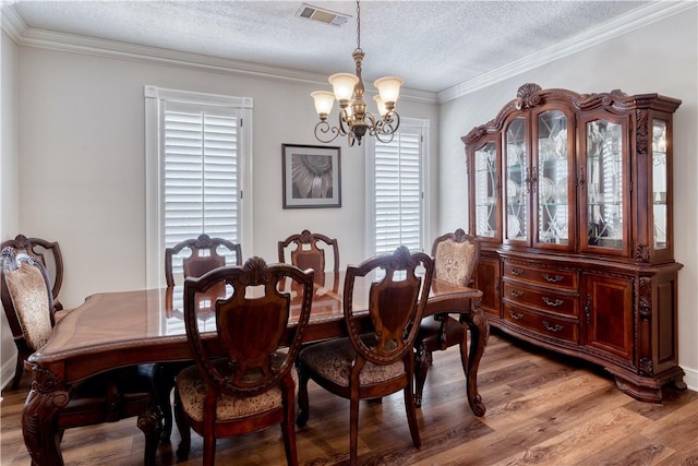 dining room featuring crown molding, light wood finished floors, visible vents, an inviting chandelier, and a textured ceiling