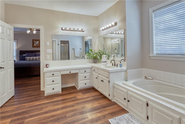 ensuite bathroom featuring connected bathroom, wood finished floors, a shower with shower door, vanity, and a bath