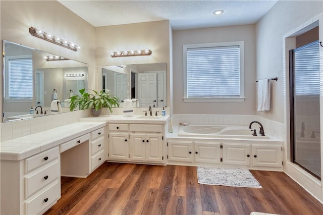 bathroom with a garden tub, a shower stall, wood finished floors, and vanity