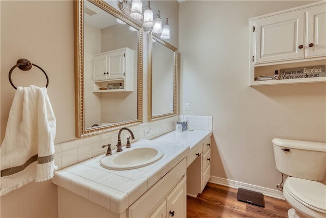 bathroom with vanity, wood finished floors, toilet, and baseboards