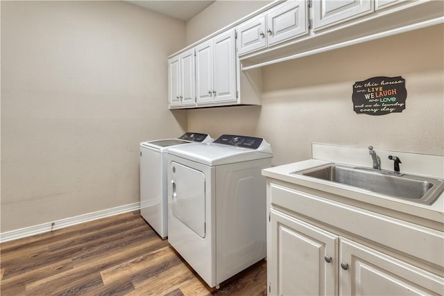 laundry area featuring cabinet space, baseboards, wood finished floors, washer and dryer, and a sink