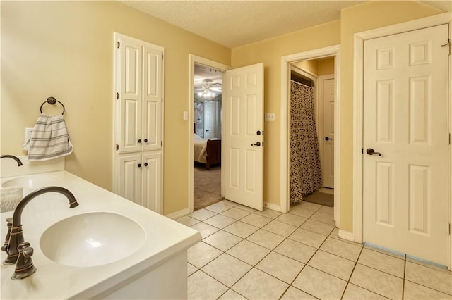 bathroom featuring a textured ceiling, ensuite bathroom, a sink, tile patterned floors, and double vanity