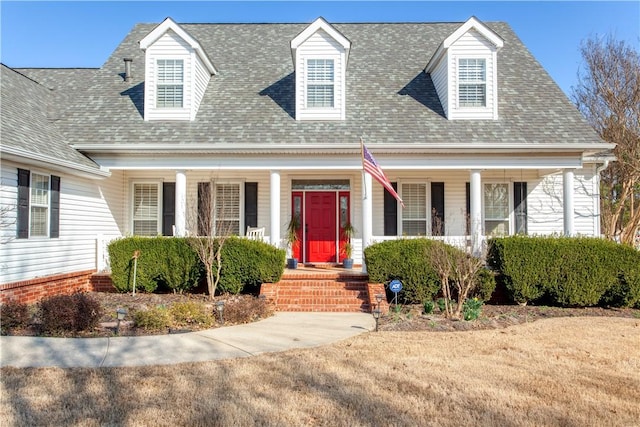 new england style home featuring covered porch and roof with shingles