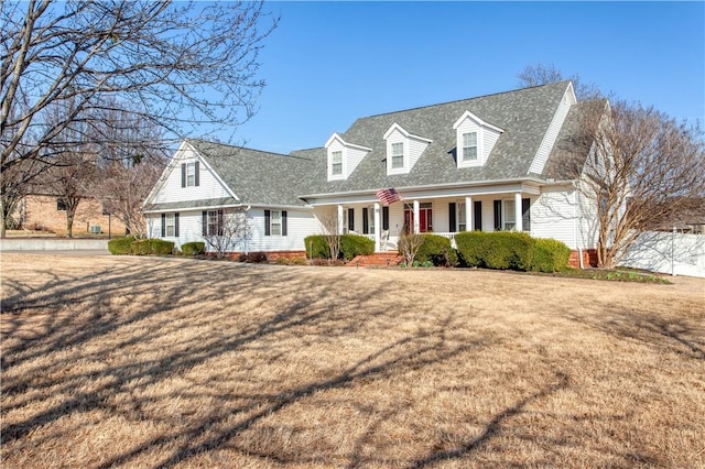 cape cod home featuring roof with shingles, a porch, and a front yard