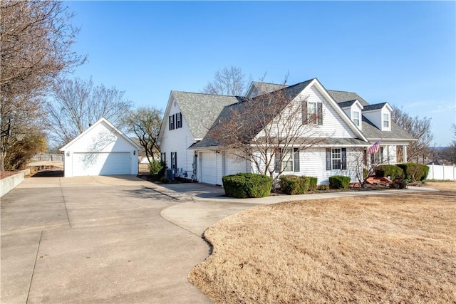 new england style home with a front yard, fence, a detached garage, and an outdoor structure