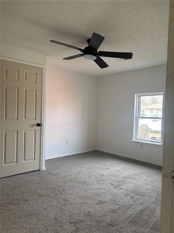 spare room with carpet floors, ceiling fan, baseboards, and a textured ceiling