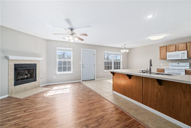 kitchen with a wealth of natural light, white appliances, a tiled fireplace, and a breakfast bar area