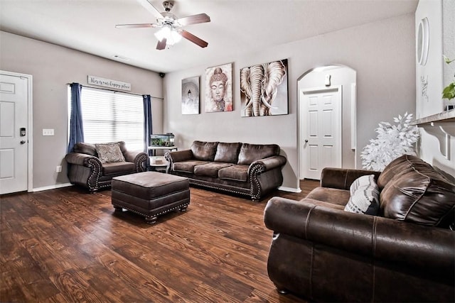 living room featuring arched walkways, wood finished floors, a ceiling fan, and baseboards